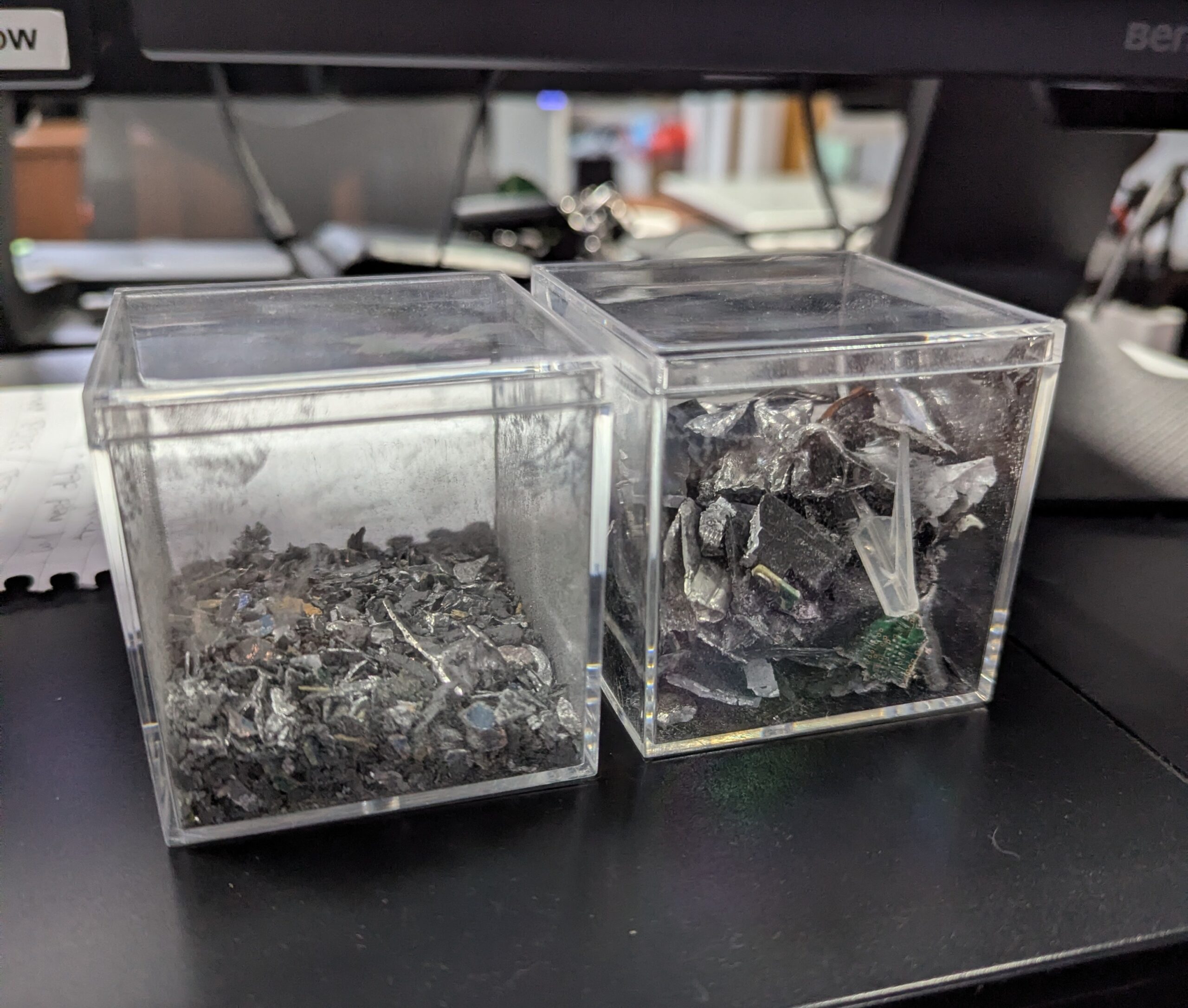 Two transparent containers showing hard drive fragments before and after shredding, demonstrating secure data destruction at BCC IT.