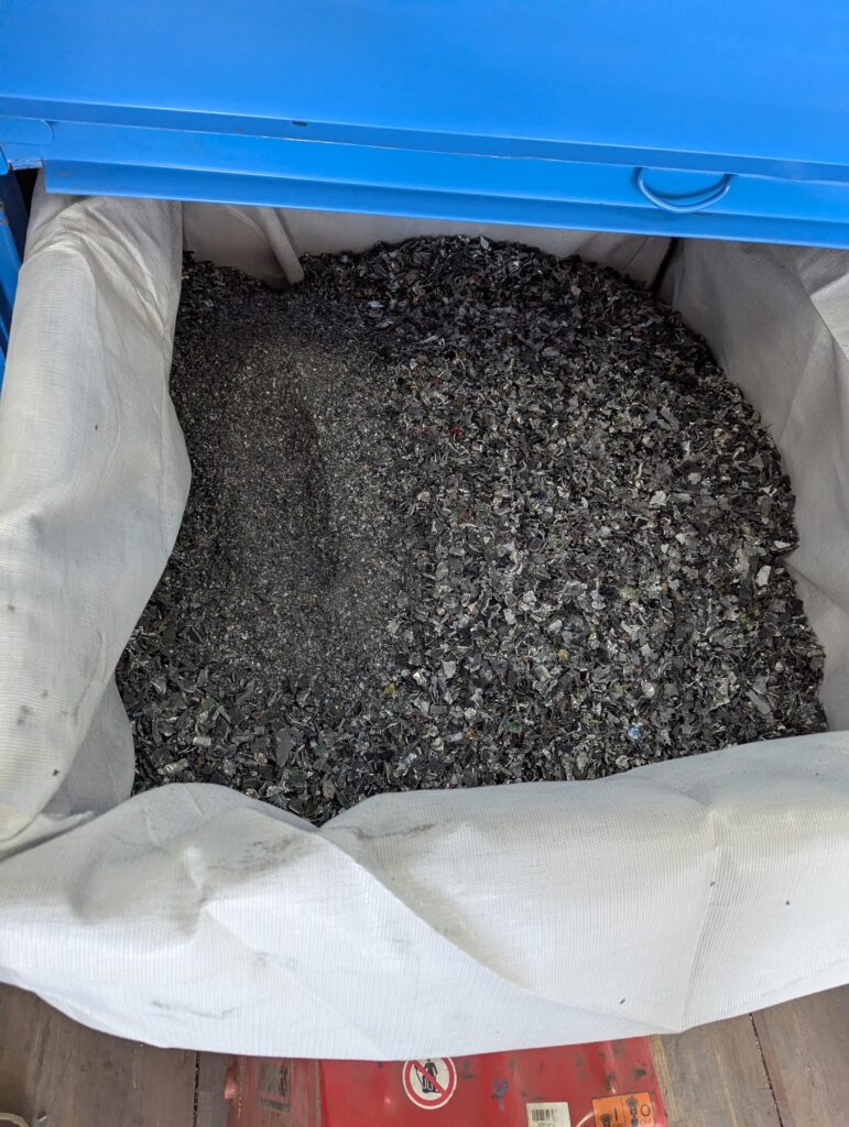 Close-up of shredded hard drive fragments collected after the destruction process.