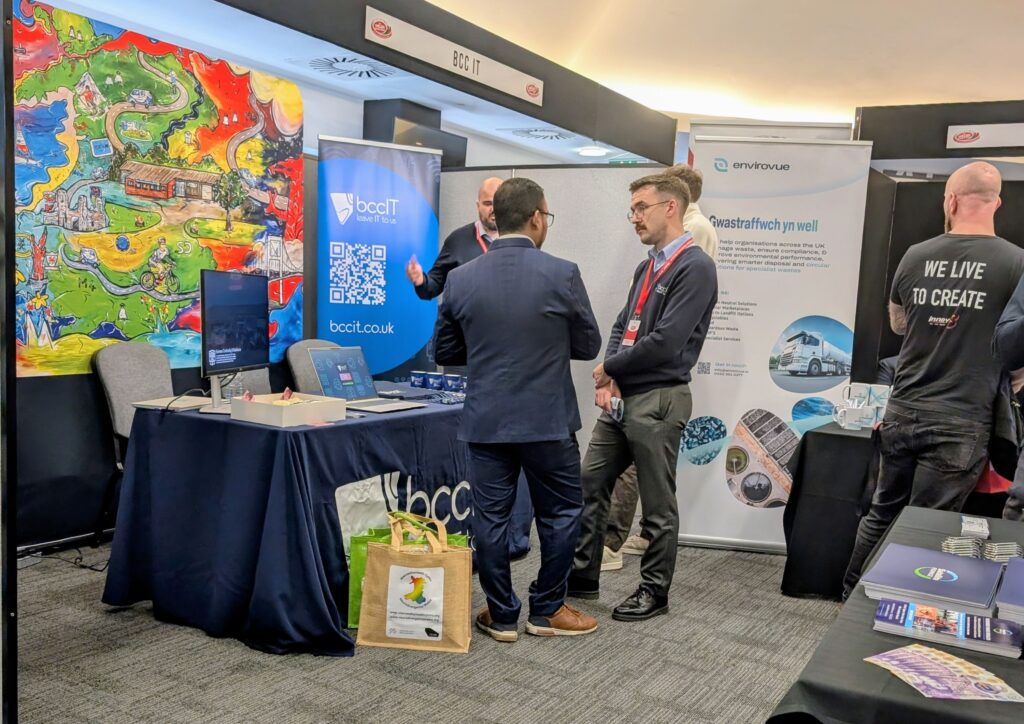 BCC IT Sales team representing the company at the Welsh Business Exhibition at Llanelli.com Stadium, standing at the company's branded stand and speaking with visitors about IT and cybersecurity solutions.