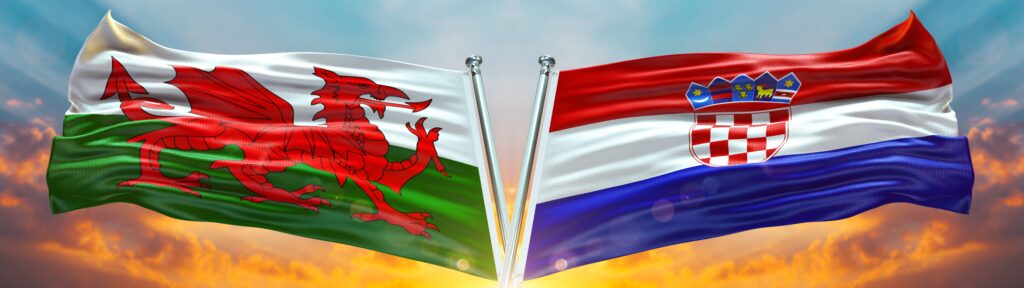 Welsh and Croatian flags waving together at sunset, symbolising teamwork, achievement, and international pride.