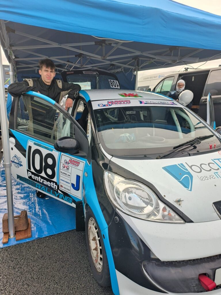 I0an Thomas with Peugeot 107 rally car in service bay during Welsh rally event
